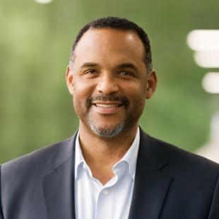 African American man with salt and pepper beard, close cut haircut, black jacket and white shirt